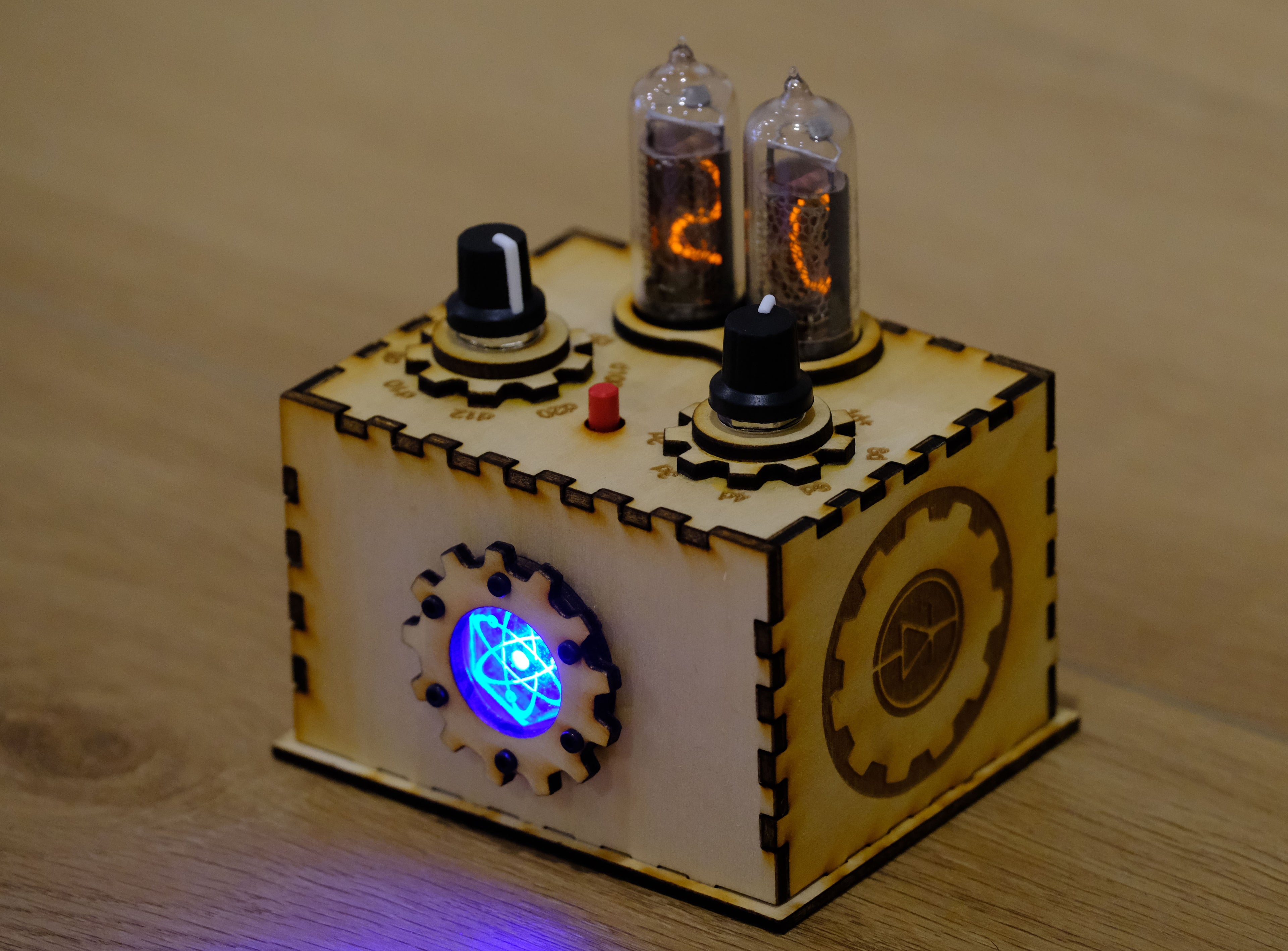 An isometric view of the Quantum Entropy Engine: Expedition. The unit is in its laser cut wooden enclosure and is powered on. The center acrylic chamber is glowing from the internal LED. The Nixie tubes are powered on and are glowing orange in color - a 20 is displayed on the display tubes.