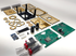 Components of a disassembled quantum entropy engine: expedition kit. The components are all laid out on a white backdrop. The components include the laser cut wooden enclosure, the PCBA holder, PCBAs, ICs and electrical components, and the Nixie tubes. View is isometric. 