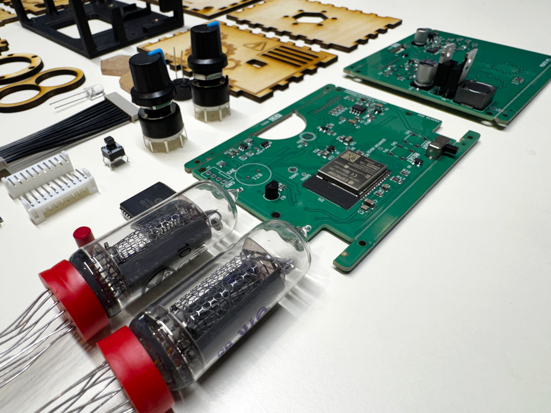 Components of a disassembled quantum entropy engine: expedition kit. The components are on a white laboratory bench. The components in the view include two circuit boards, some electrical components, and a close up view of the Nixie tubes.
