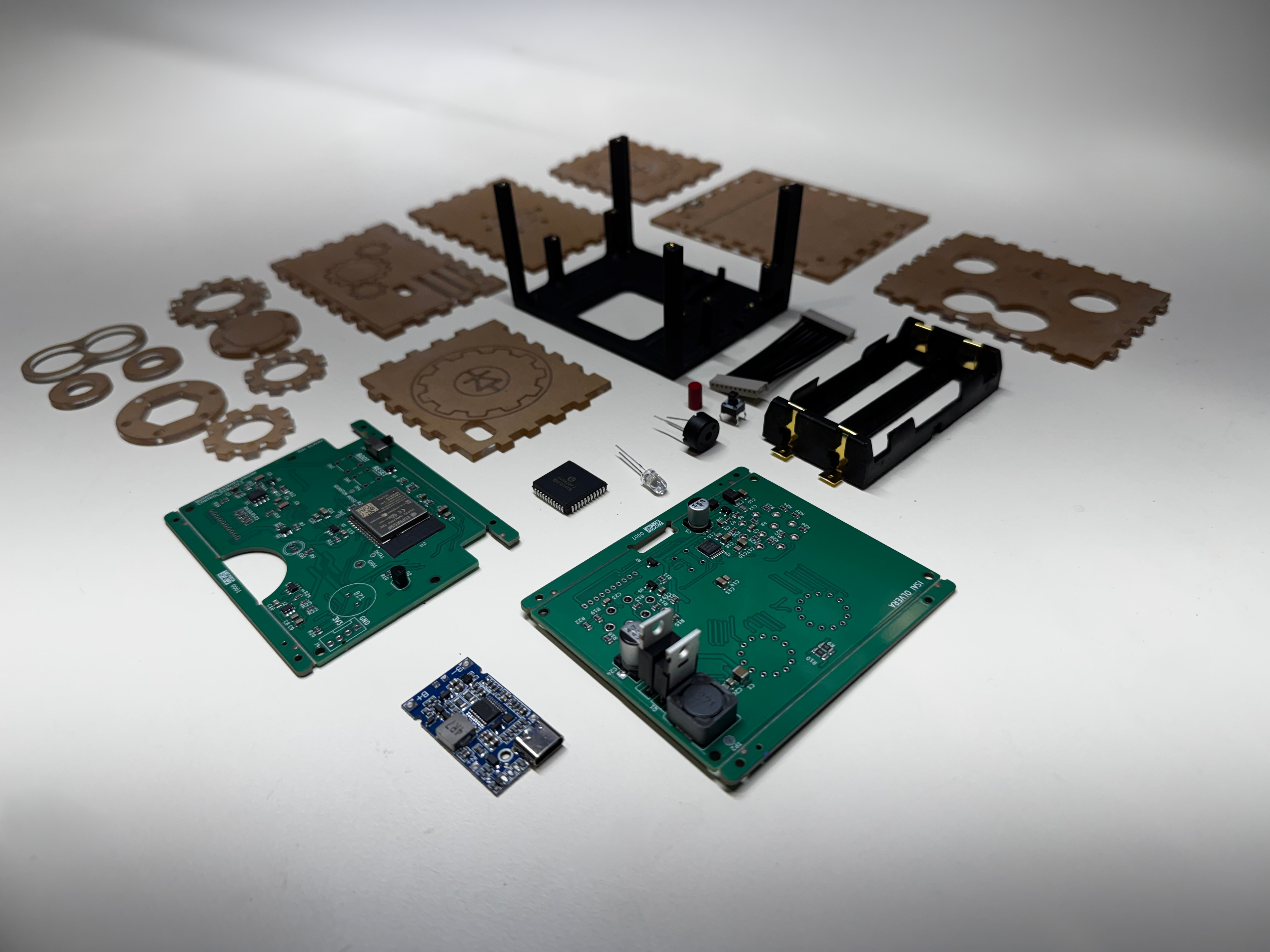 Components of a disassembled quantum entropy engine: expedition kit. The components are on a white laboratory bench. The components in the view include two circuit boards, some electrical components (rotary knobs, board to board cable harness, JST connectors, a high voltage display IC), the charging PCBA, and the Nixie tubes. Laser cut, paper-backed, acrylic enclosure components are visible. 