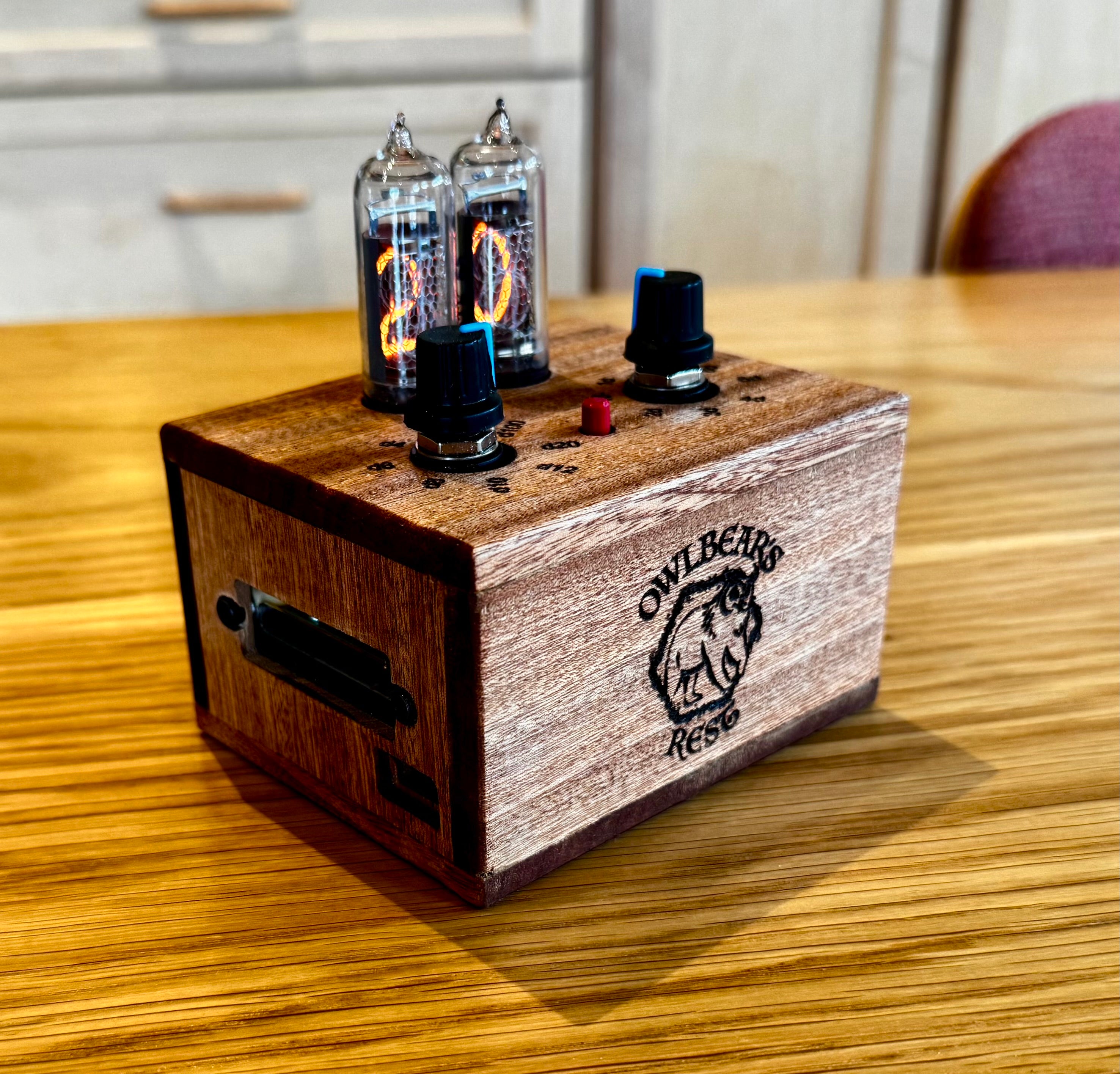 Wooden quantum entropy engine with Nixie tubes showing the number 20. A custom laser engraved logo is at the front of the box. 