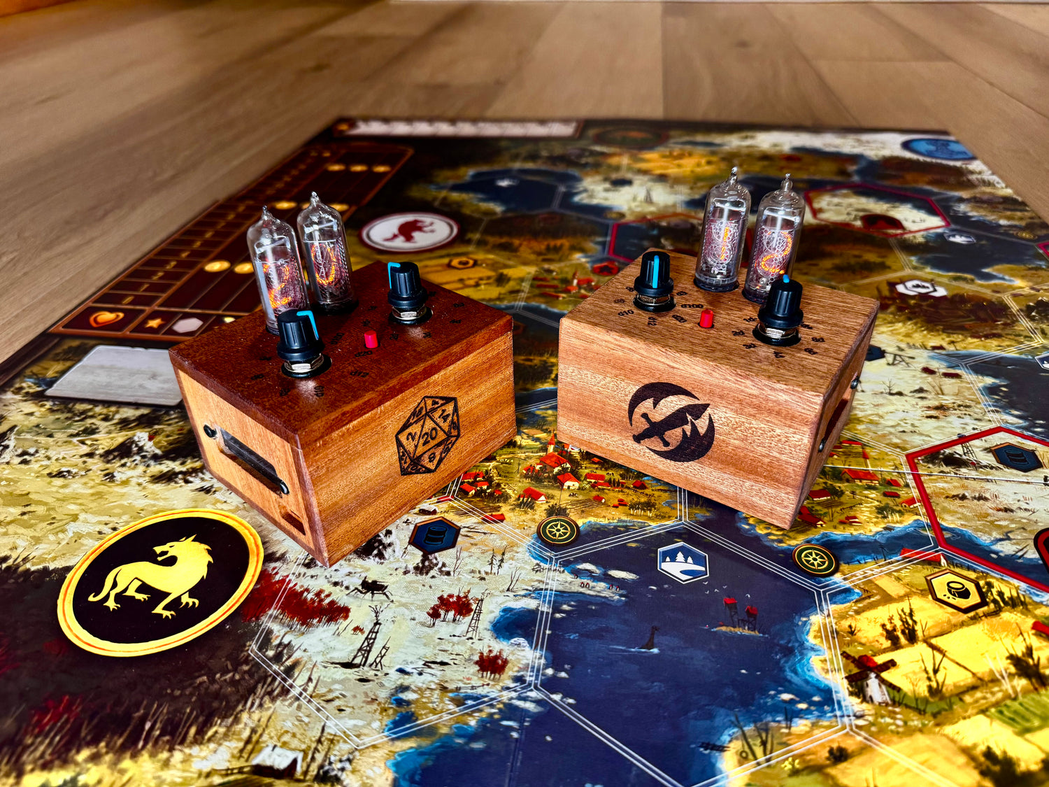 Two quantum entropy engines of mahogany wood sit on a board game setup. The two boxes display different wood engraved logos.