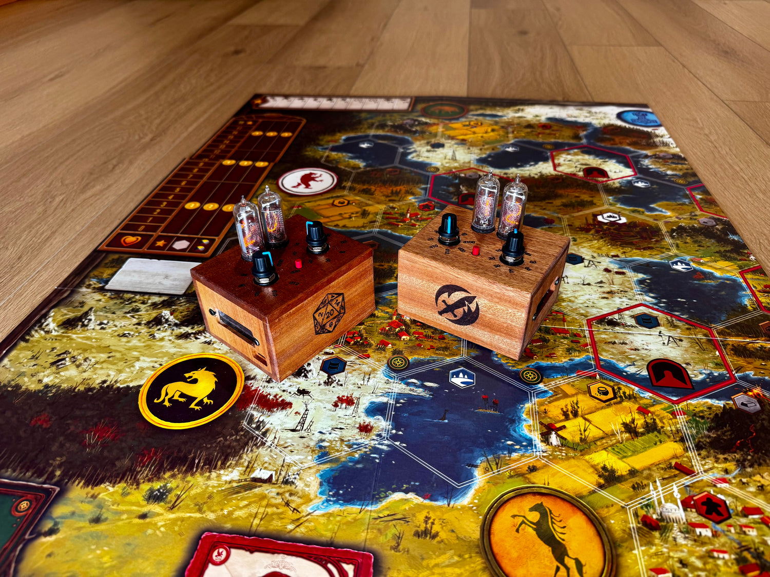 Board game setup with two mahogany quantum entropy engines. Two different logos are laser engraved on the front. The right enclosure highlights the different die types that are available to roll.